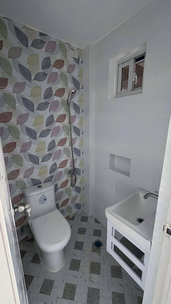 Private bathroom with shower, toilet and wash basin, finished in patterned tile.